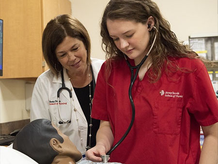 A nursing student using a stethoscope.
